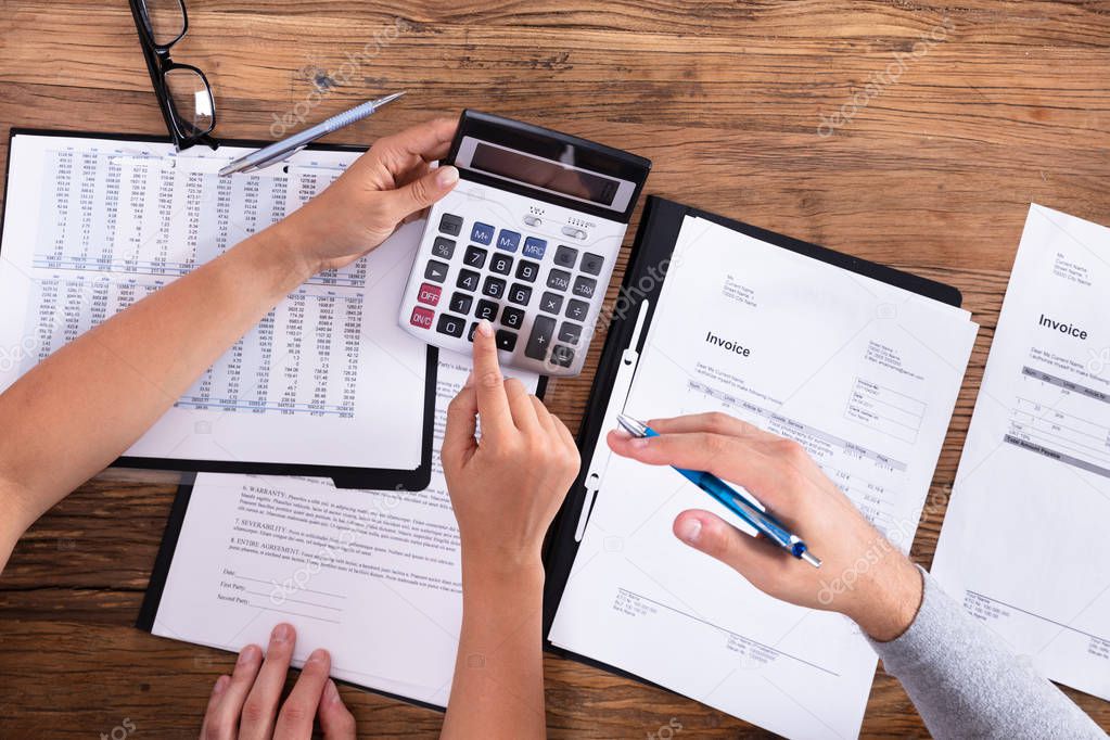 Elevated View Of Couple Calculating Bill With Calculator On Wooden Background