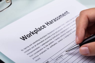 Close-up Of A Woman's Hand Filling Workplace Harassment Form clipart