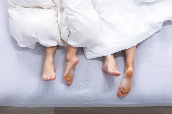 Voeten Van Paar Bed Onder Witte Beddelaken — Stockfoto