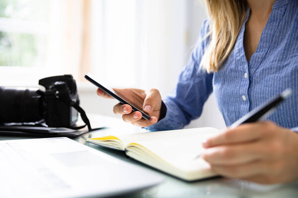 Рука редактора с расписанием записи мобильного телефона в дневнике
