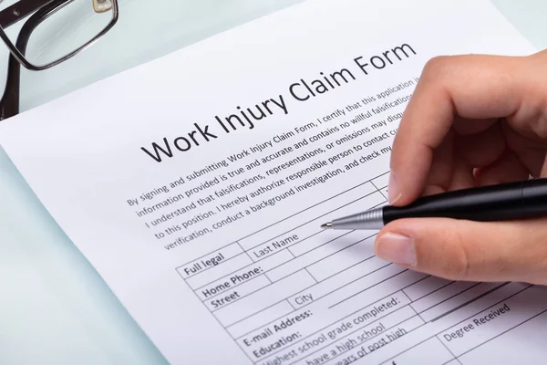 Close Woman Hand Filling Work Injury Claim Form Stock Photo