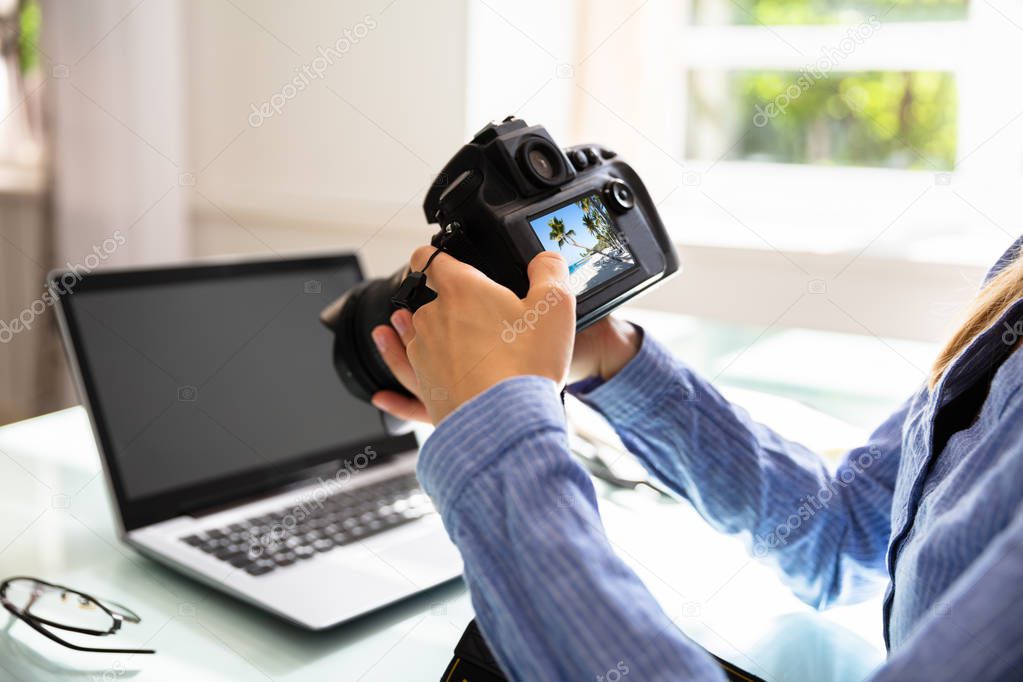 Close-up Of An Editor Looking At Photograph In DSLR Camera At Workplace