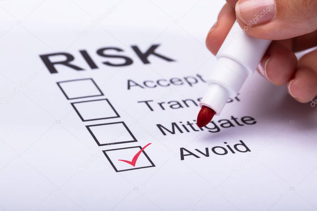 Close-up Of A Woman's Hand Ticking Avoid Option On Risk Form With Marker