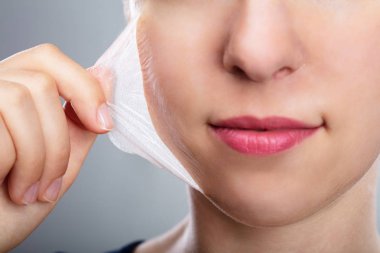 Yüzünü maske Peeling kaldırma güzel bir genç kadının portresi