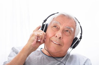Evde müzik kulaklık üzerinde dinlemek üst düzey bir adam portresi