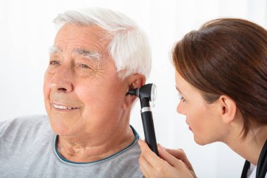 Yakın çekim, kıdemli erkek hastanın kulak mastar ile inceleyerek bir erkek doktor