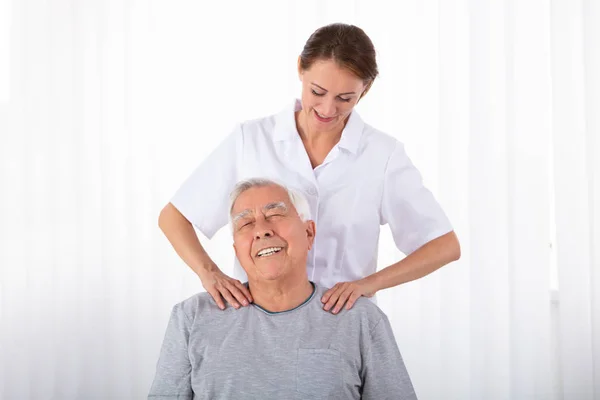 Joven Fisioterapeuta Masajeando Hombro Hombre Senior Clínica —  Fotos de Stock