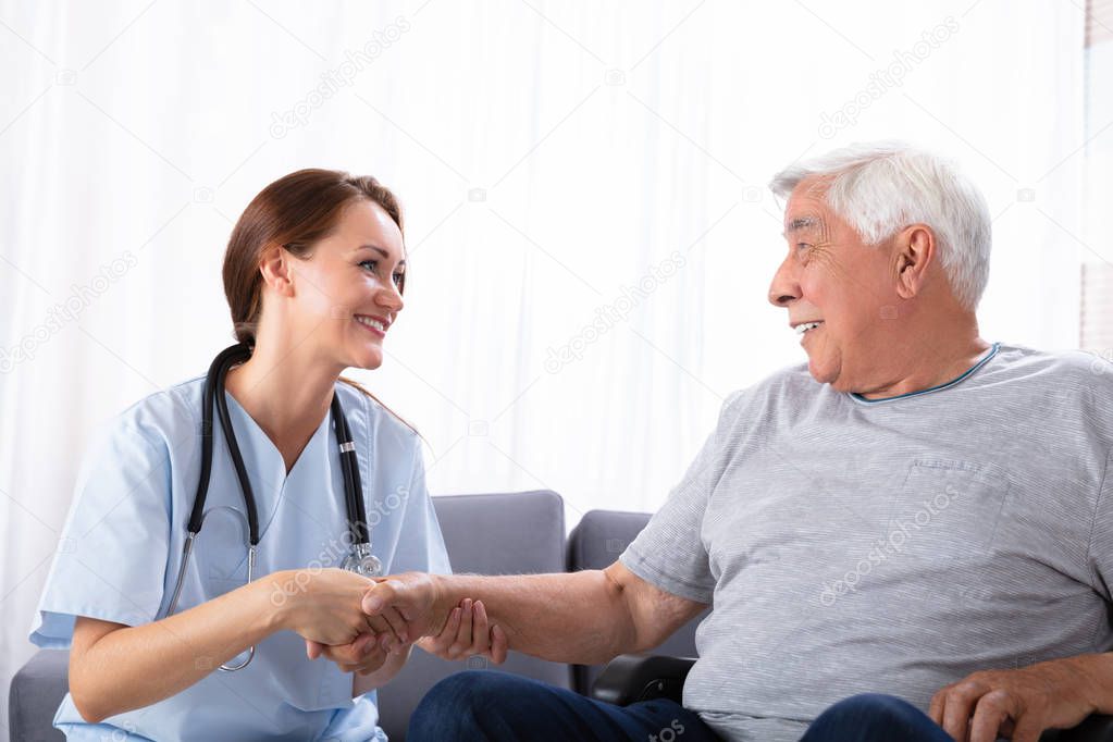 Portrait Of A Happy Female Nurse Looking At Senior Man