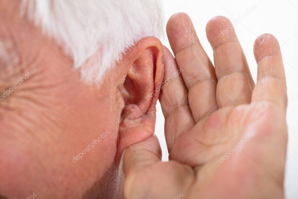 Portrait Of A Senior Man's Hand Trying To Hear After Inserting Hearing Aid