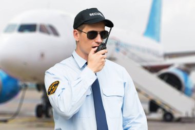 Erkek güvenlik görevlisi volki tolki bir Havaalanı'nda konuşurken portresi