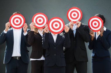 Yüzlerini dart tahtası gri arka plan üzerinde arkasında saklanıyor işadamları grubu