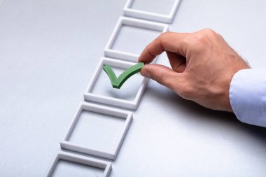 Adamın elini kutusunda gri arka plan üzerinde yeşil onay işareti yerleştirme
