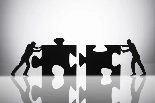 Silhouette Two Businesspeople Joining Jigsaw Puzzle Pieces Reflective Desk — Stock Photo, Image