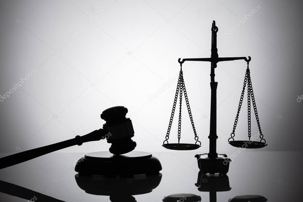 Silhouette Of Gavel And Justice Scale On Reflective Background