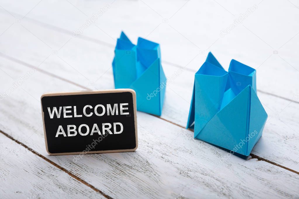 Close-up Of Welcome Aboard Text On Slate Over Wooden Desk