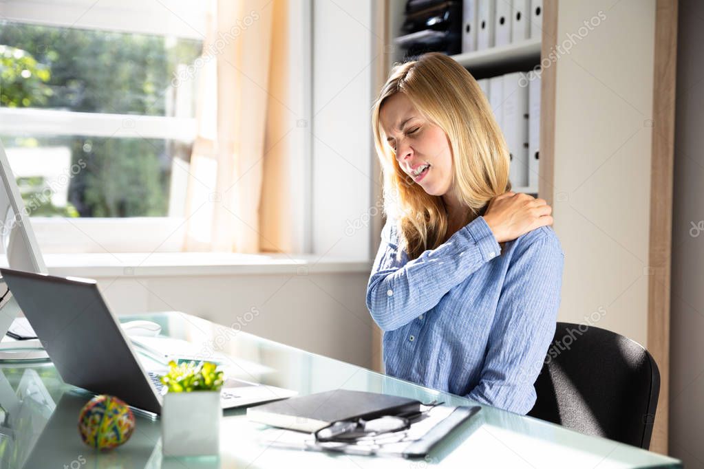 Young Businesswoman Suffering From Neck Pain Sitting In Office