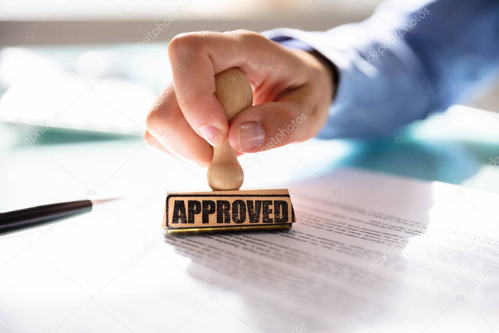 Close-up Of A Businesswoman's Hand Stamping On Approved Contract Form