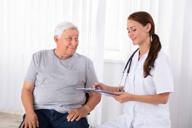 Gülümseyen genç doktor erkek hastada klinik reçete verilmesi Pano ile