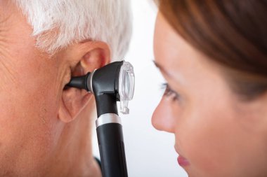 Yakın çekim, kıdemli erkek hastanın kulak mastar ile inceleyerek bir erkek doktor