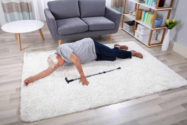 自宅のカーペットの上に横たわって杖と無意識の年配の男性 — ストック写真