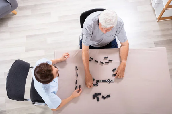 女性管理人と年配の男性がドミノをプレイの立面図 — ストック写真