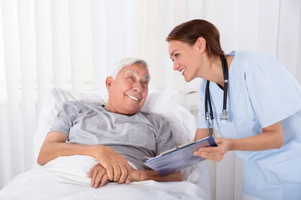 Ung Kvinna Sjuksköterska Med Urklipp Besöker Senior Manlig Patient — Stockfoto