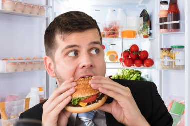 Genç işadamı Burger önünde açık bir buzdolabı yemek