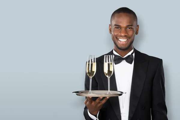 Portrait Smiling African Waiter Holding Champagne Drink Gray Background — Stock Photo, Image