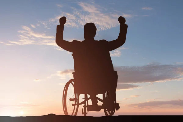 Silueta Hombre Discapacitado Silla Ruedas Con Brazo Levantado Atardecer —  Fotos de Stock