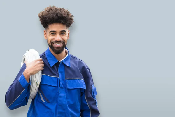 灰色の背景にケーブル コイルと幸せな男性の電気技師の肖像画 — ストック写真