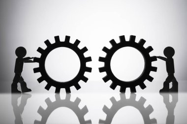 İki insan figürü bağlanma Gears yansıtıcı arka plan üzerinde silüeti