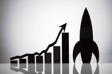 Roket yanı sıra grafik yukarı yönde hareket yansıtıcı arka plan üzerinde bir ok ile silüeti