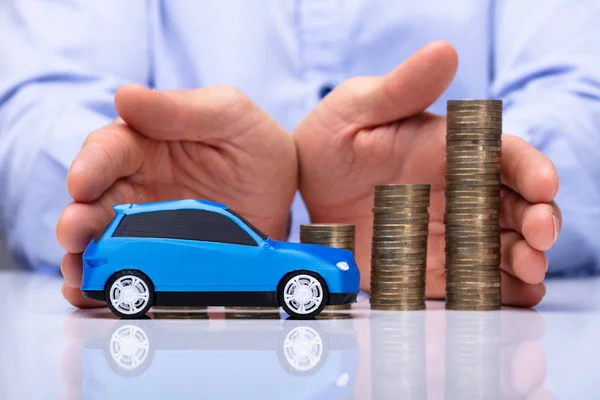 Männerhand Schützt Blaues Auto Und Wachsende Münzen Auf Reflektierendem Schreibtisch — Stockfoto