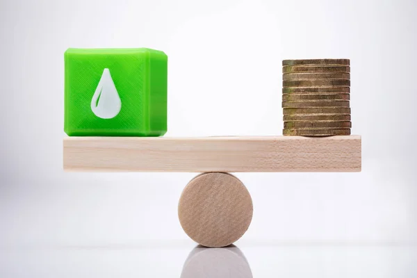 Green Cubic Block Waterdrop Icon Stacked Coins Balancing Wooden Seesaw Stock Photo