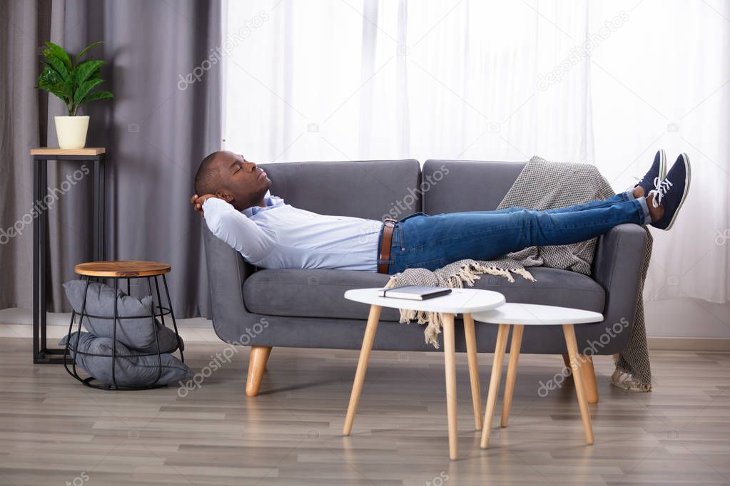 Young African Man Sleeping On Sofa At Home