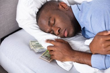 Afrika adam yatakta para birimi notlar bohça ile uyku
