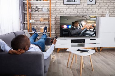 Evde televizyon izlerken kanepede yatan adam