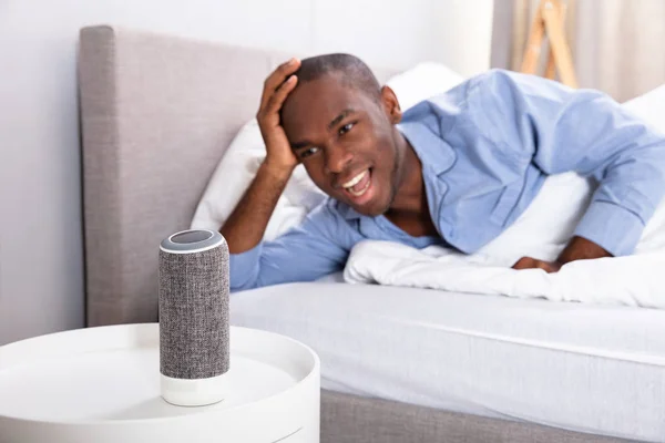 Africano Uomo Sdraiato Sul Letto Ascolto Musica Altoparlante Wireless — Foto Stock