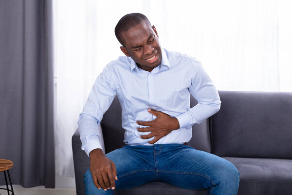 Крупный план молодого африканца с болью в животе
