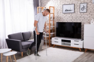 Halıda yürümek koltuk değneği kullanarak Engelli genç adam