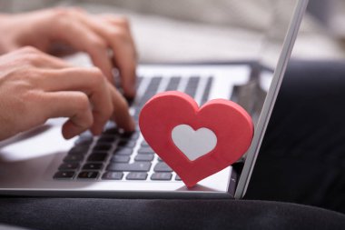 Kişinin el Laptop tuş takımı kırmızı kalp ile yazarak