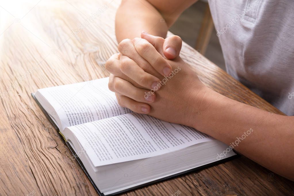Sunlight Falling On Hand Over Bible While Praying