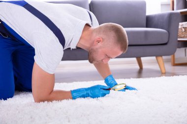 Genç erkek hademe halı büyüteç ile bakarak yan görünüm