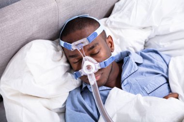 Yatakta uyuyan Cpap maske takıyor bir Afrika gencin yüksek açılı görünüş