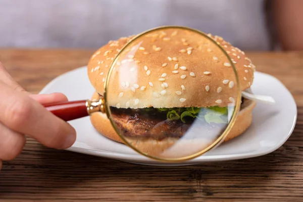 Man Hand Holding Nagyító Friss Hamburger Mutatása — Stock Fotó