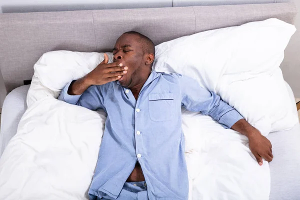 Vista Elevada Jovem Homem Africano Sonolento Bocejando Cama — Fotografia de Stock