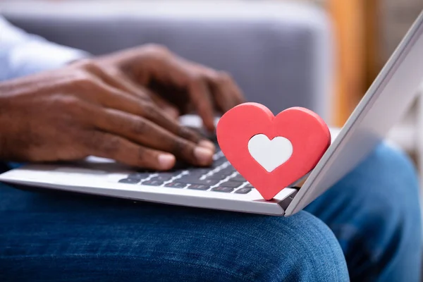 在键盘上特写红色的心形 而人的手使用笔记本电脑 — 图库照片