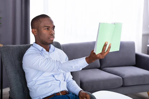 Ung Afrikansk Man Sitter Stol Innehav Bok Hemma — Stockfoto