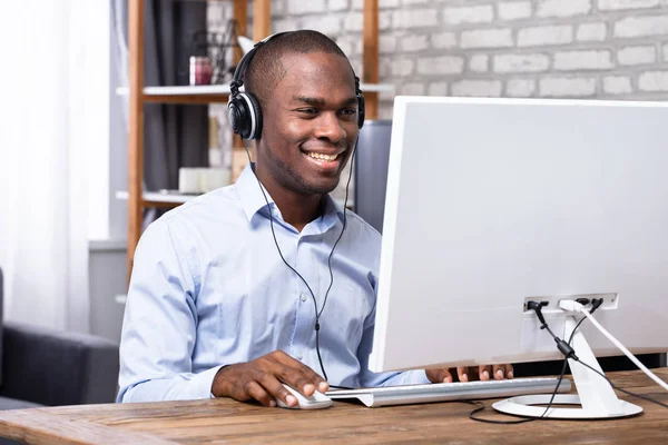 Homem Sorridente Ouvindo Música Fone Ouvido Usar Computador Sobre Mesa — Fotografia de Stock