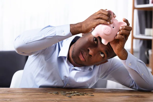Afrikaanse Man Controleren Besparingen Iggybank Met Munten Houten Bureau — Stockfoto